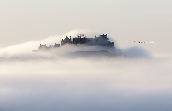 Stirling Castle in Scotland amidst a sea of mist with a fly-past by a flock of geese